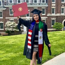 woman wearing college graduation robe holding a diploma up
